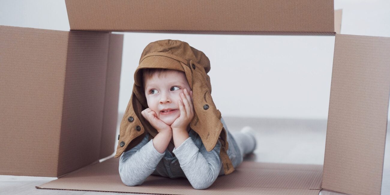 Child preschooler boy playing inside paper box. Childhood, repairs and new house concept